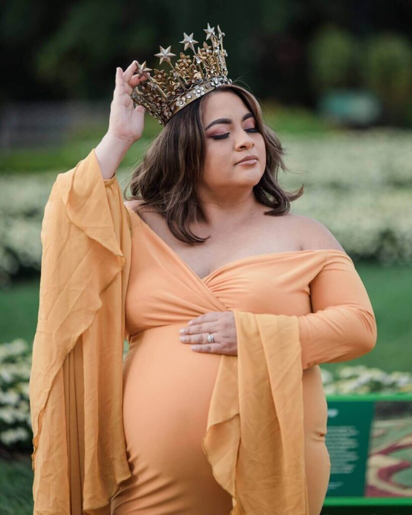 Pregnant woman in beautiful yellow dress and crown for maternity outdoor photoshoot